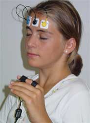 Young woman with biofeedback monitors on her forhead and index finger.